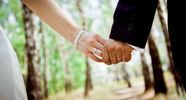 Bride and groom holding hands in forest.