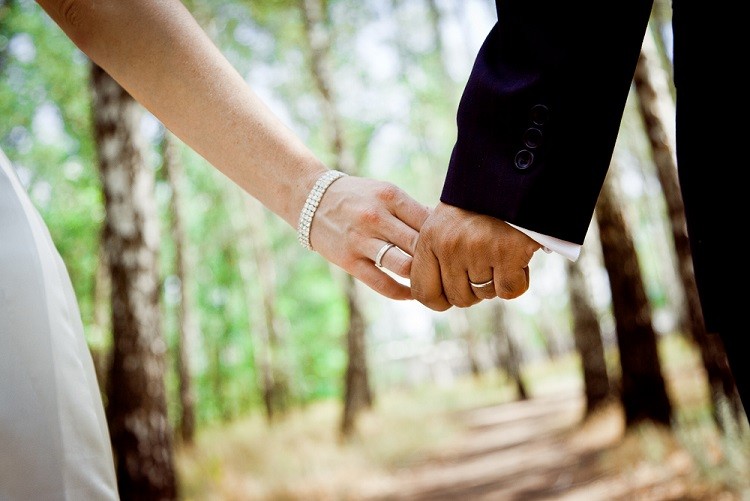 Bride and groom holding hands in forest.