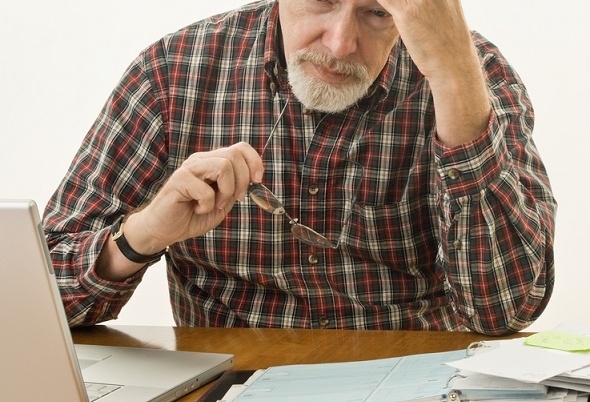 An older man stressed with paperwork.