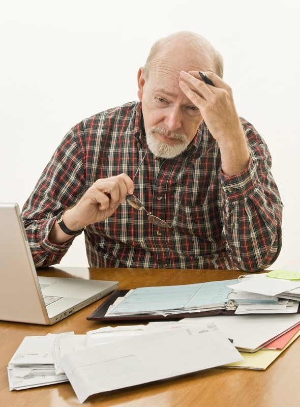 An older man stressed with paperwork.