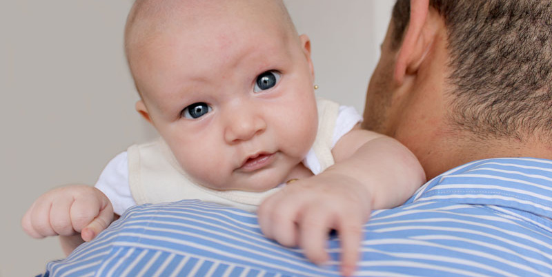 Baby on father's shoulder, blue stripes.