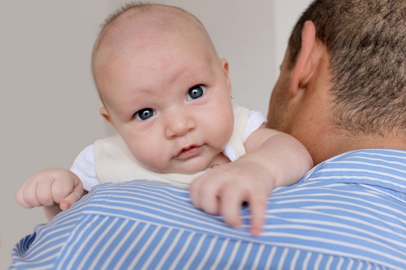 Baby on father's shoulder, blue stripes.