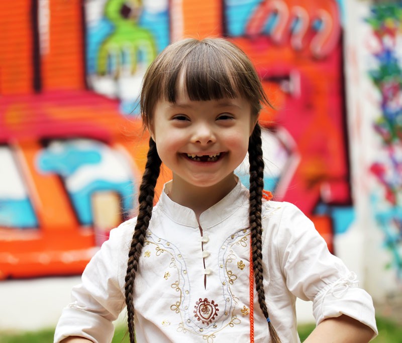 Smiling girl with braids in front of graffiti.