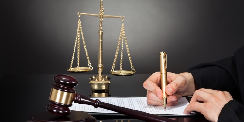 a judge signing a document with a gavel on the table