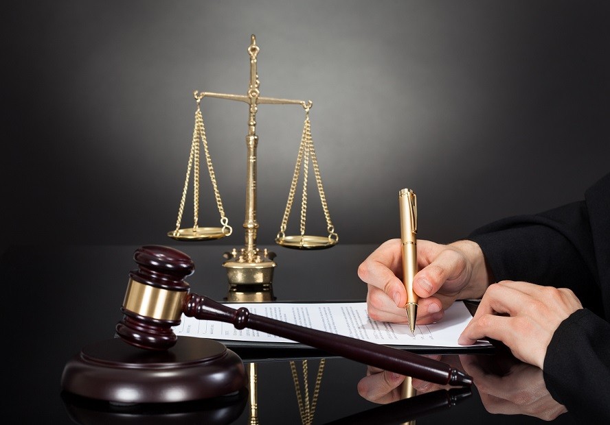 a judge signing a document with a gavel on the table